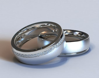 Könnte beinhalten: Zwei silberne Eheringe, einer mit einer Reihe kleiner Diamanten am Rand.