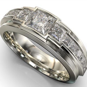 May include: A silver-toned ring featuring three large, square-cut diamonds set in a geometric design. The band is accented with smaller, pave-set diamonds, creating a luxurious and elegant appearance. This ring is a statement piece of jewelry.