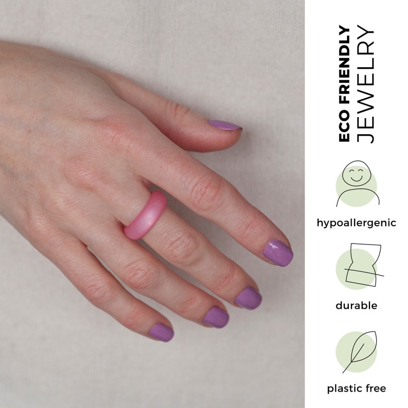 May include: A pink silicone ring on a hand with purple nail polish. The ring is described as eco-friendly, hypoallergenic, durable, and plastic free.