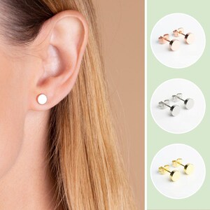 May include: A close-up of a person's ear with a small, round, silver stud earring. The image also shows three different colour options for the earring: rose gold, silver, and gold.