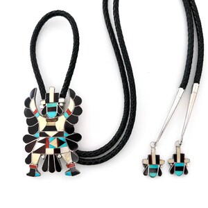 May include: A bolo tie with a silver and turquoise pendant featuring a Native American design. The bolo tie has a black cord and silver tips. The pendant is detailed with intricate geometric patterns and colorful stones.