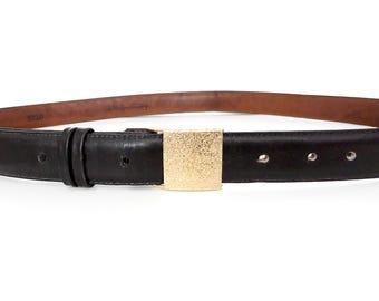 May include: A black leather belt with a gold-colored square buckle. The belt has a brown interior and several holes for adjustment. The buckle has a textured surface. The belt is a classic accessory.