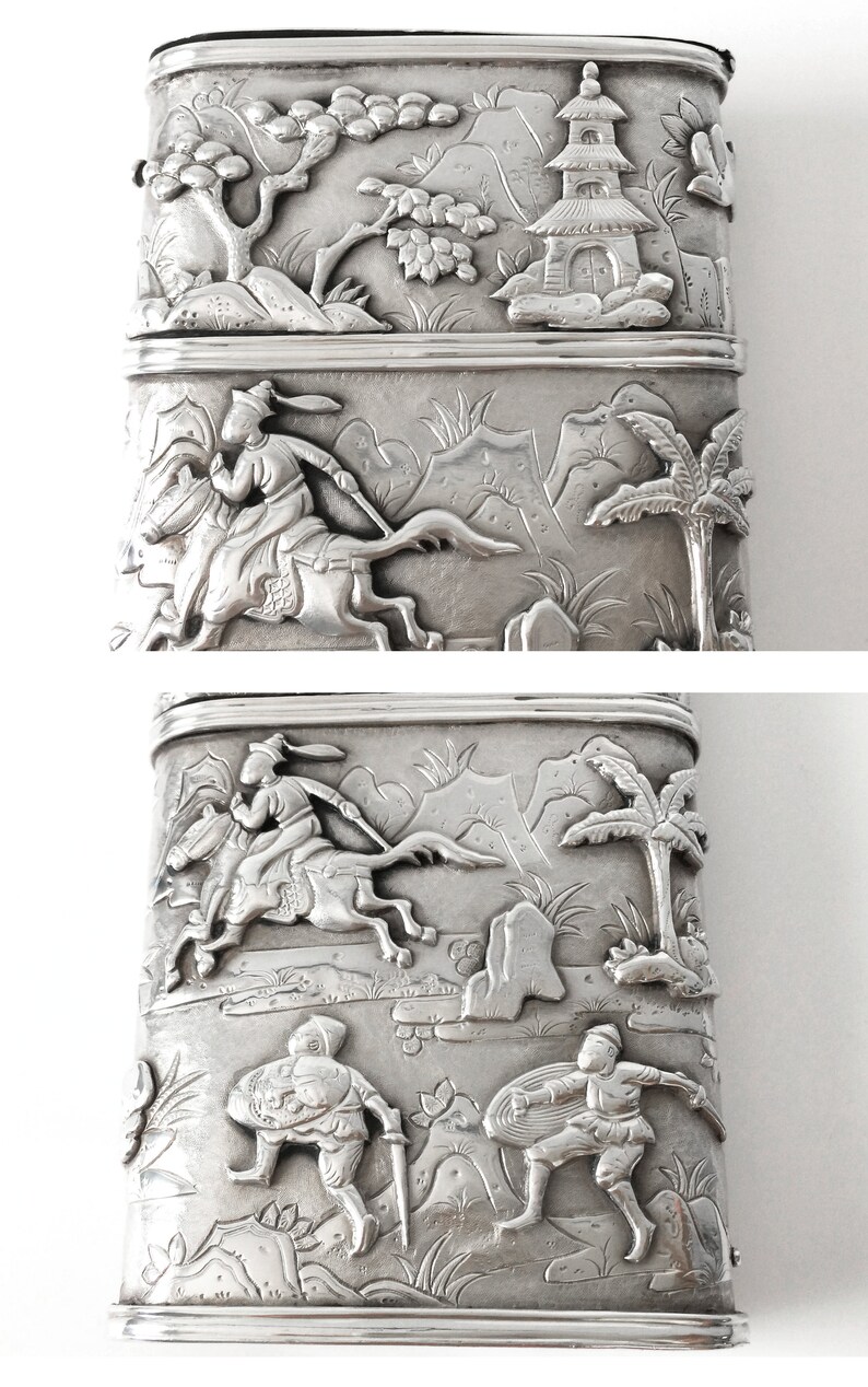 May include: A silver rectangular box with intricate embossed designs. The top and bottom sections feature scenes of people riding horses and palm trees. The middle section shows a pagoda and trees.