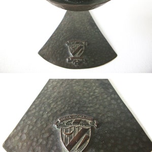Puede incluir: Un candelero de bronce con acabado martillado y un escudo con el texto "Beta Sigma Phi" y "Via Scientia Amicitia".
