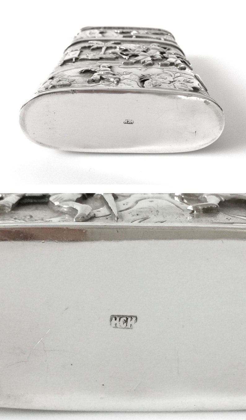 May include: Silver flask with an ornate design featuring figures and flowers. The bottom of the flask is marked with the letters "HCH".