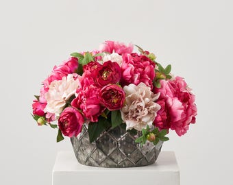 May include: A bouquet of pink and white peonies arranged in a silver, textured vase. The vase has a diamond pattern.