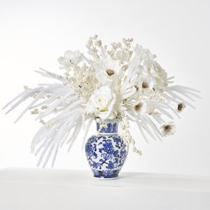 Arreglo navideño de invierno con tacto real flocado en Norfolk, rosa de invierno y baya perlada en jarrón chinoiserie azul y blanco
