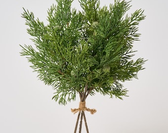 May include: An artificial cedar bush with green foliage and small green berries. The bush is tied together with twine.