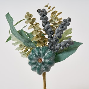 May include: A green faux pumpkin with a stem, surrounded by sprigs of eucalyptus and faux berries. The berries are a dark blue colour.