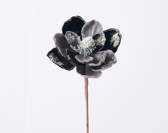 May include: A single artificial flower with black and silver petals and a brown stem. The flower's center is adorned with small, sparkling embellishments. The petals have a glittery finish, adding a touch of glamour.