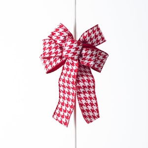 Puede incluir: Un lazo de color rojo y blanco con estampado de pata de gallo con un tallo blanco.