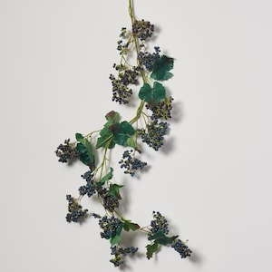 May include: A long garland of artificial greenery with dark blue berries. The garland is perfect for adding a touch of nature to your home decor.