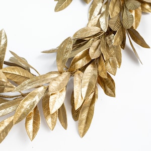 May include: A gold leaf garland with a realistic look. The garland is made of artificial leaves and is perfect for adding a touch of elegance to any space.
