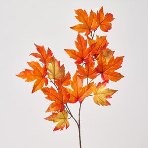 May include: A branch of artificial maple leaves in shades of orange, red, and yellow. The leaves are clustered along a brown stem, creating a fall-themed decorative element. The leaves have detailed veining.