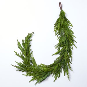 May include: A green artificial pine garland with a brown leather loop for hanging.