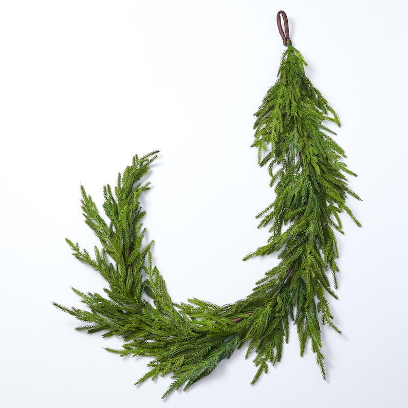 May include: A green artificial pine garland with a brown leather loop for hanging.