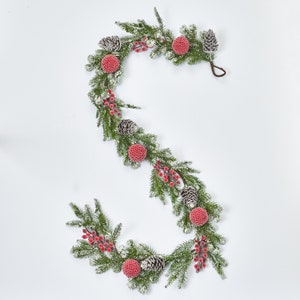 May include: A festive garland featuring frosted pine branches, red berries, and pinecones. The garland is decorated with red and white baubles.