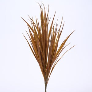 May include: A bundle of artificial ornamental grass with long, slender, brown and gold blades. The faux plant has a natural appearance and is suitable for home decor or floral arrangements. The grass is set against a white background.