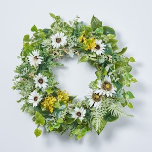 May include: A green wreath with white flowers and yellow flowers. The wreath is made of artificial greenery and flowers.