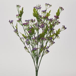 May include: A bunch of artificial purple flowers with green stems and leaves. The flowers are small and clustered together.