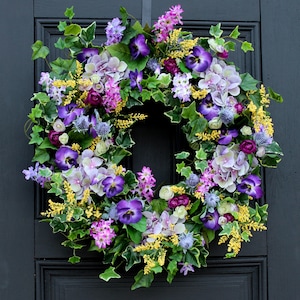 Corona de primavera para puerta con hortensias de lavanda real, lilas, pensamientos morados y astilbe amarilla.