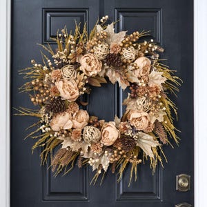 Può includere: Una ghirlanda autunnale beige e marrone con peonie finte, pigne e erbe secche.