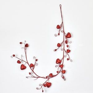 Può includere: Una ghirlanda di cuori rossi glitterati con un gambo di filo metallico. La ghirlanda è composta da piccoli cuori rossi collegati da un gambo di filo metallico. La ghirlanda è perfetta per decorare per San Valentino o altre occasioni speciali.