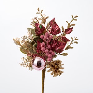 May include: A pink and gold Christmas floral spray with a pink glitter ball ornament, burgundy leaves, and gold pine cones.