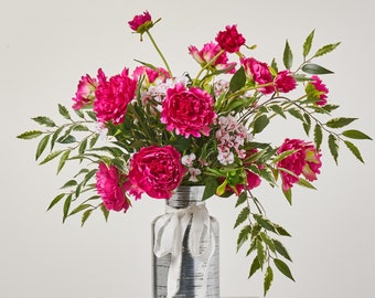 May include: A bouquet of pink peonies arranged in a silver vase with a white ribbon. The flowers are in full bloom and have a lush, vibrant appearance.