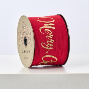 Op de afbeelding: Een rol rood satijnen lint met gouden geborduurde "Merry Christmas" belettering. Het lint is 2,5 inch breed en is gemaakt door d. stevens fine ribbons.