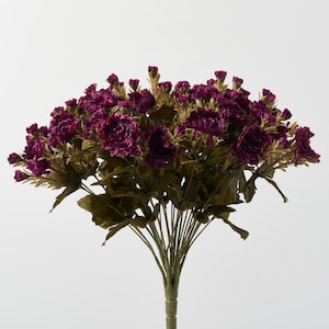 Peut inclure: Un bouquet de œillets artificiels violets avec des feuilles vertes.