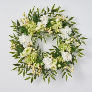 Peut inclure: Une couronne florale verte et blanche avec des hortensias blancs, des feuilles vertes et de petites baies jaunes.