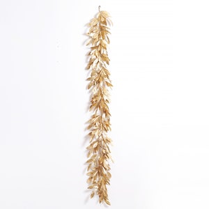 May include: A gold leaf garland with a long, flowing design. The garland is made of artificial leaves and is perfect for adding a touch of elegance to any space.