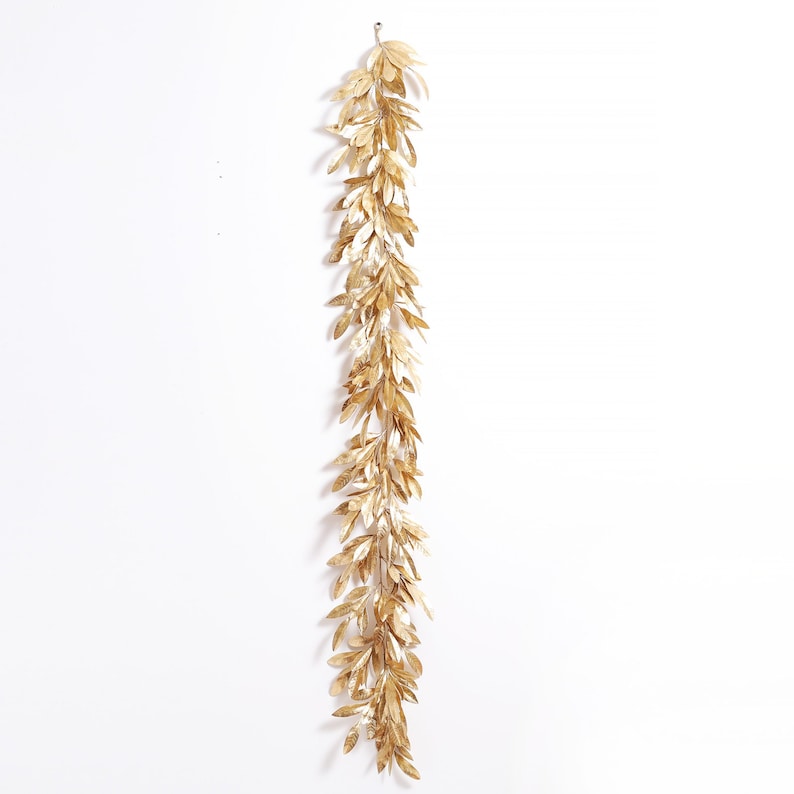 May include: A gold leaf garland with a long, flowing design. The garland is made of artificial leaves and is perfect for adding a touch of elegance to any space.