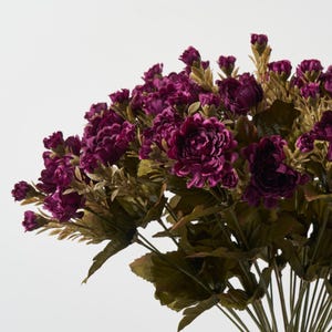 May include: A bouquet of artificial flowers with deep purple blooms and green leaves.