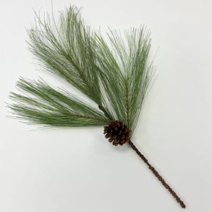 May include: A single artificial pine sprig with a brown pine cone. The sprig is green and has a long, brown stem.