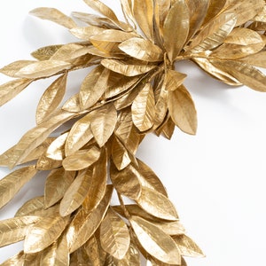 K&ouml;nnte beinhalten: Ein goldener Kranz aus k&uuml;nstlichen Bl&auml;ttern, perfekt, um Ihrer Wohnkultur einen Hauch von Eleganz zu verleihen.