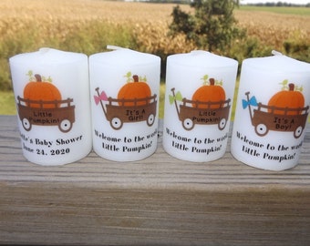 May include: Four white pillar candles with fall-themed designs. Each candle features a pumpkin in a wagon with the text "Little Pumpkin!" and "It's a Girl!" or "It's a Boy!" One candle also has the text "Welcome to the world Little Pumpkin!" and "It's Baby Shower June 24, 2020".