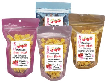 May include: Several clear cellophane bags filled with popcorn. Each bag has a label with the text "Thank you Berry Much" and a strawberry design. The labels also include the text "FOR SHOWERING OUR BABY WITH LOVE!" and "Baby Lucy Arriving August 2026."