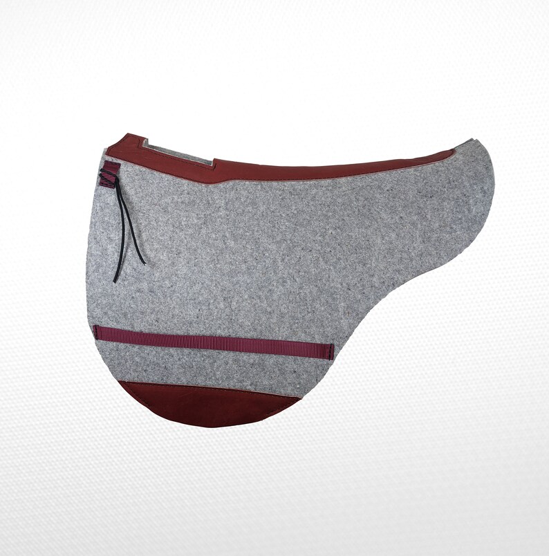 May include: A gray felt saddle pad with a burgundy trim and a black strap. The pad has a burgundy felt underside.