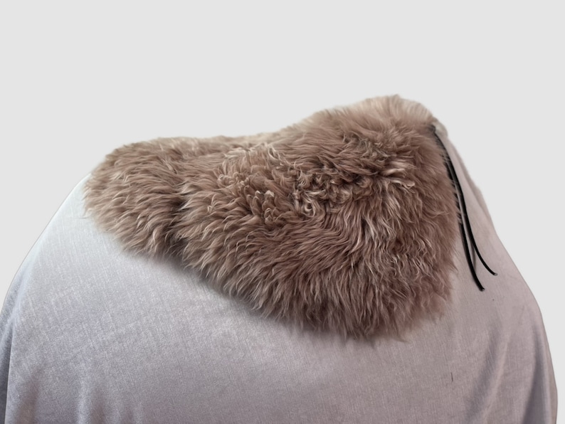 May include: A light brown sheepskin saddle pad with black leather ties.