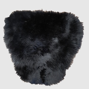 May include: A black sheepskin rug with a soft, fluffy texture.