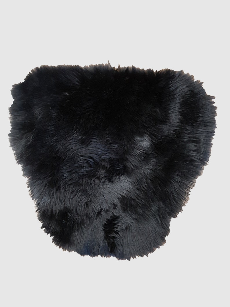May include: A black sheepskin rug with a soft, fluffy texture.