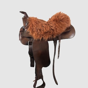 May include: A brown leather saddle with a brown faux fur seat cover.