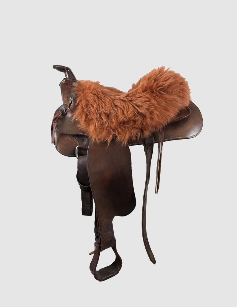 May include: A brown leather saddle with a brown faux fur seat cover.