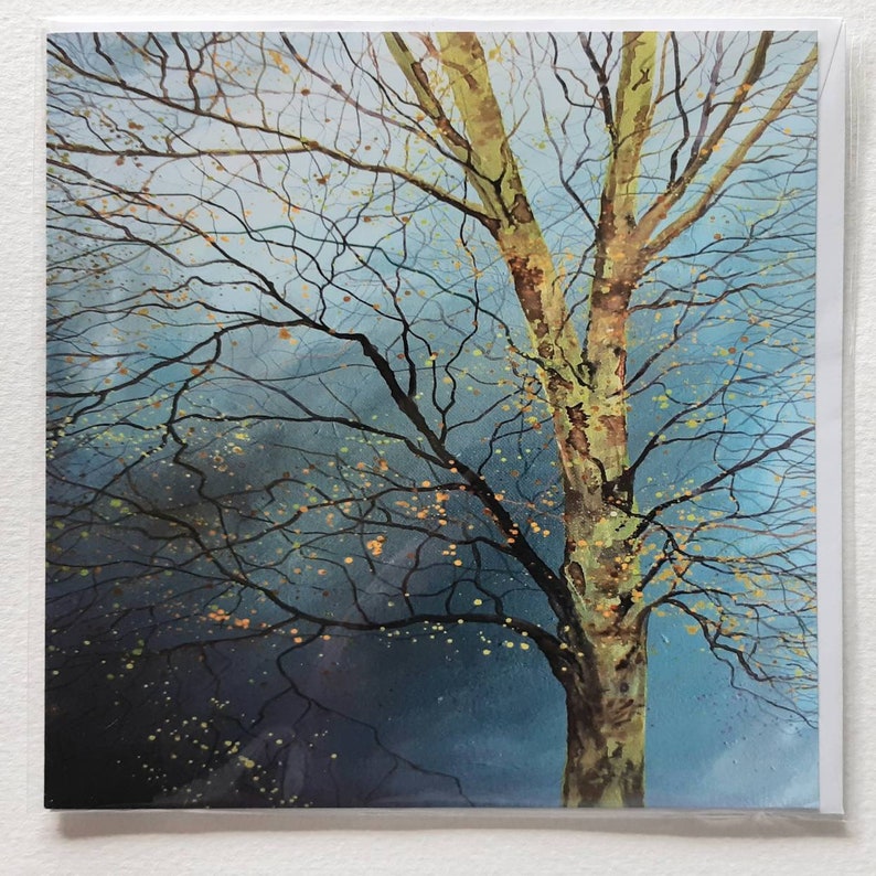 May include: A watercolor painting of a tree with a blue background. The tree has a light brown trunk and branches with yellow leaves. The background is a light blue with darker blue accents.
