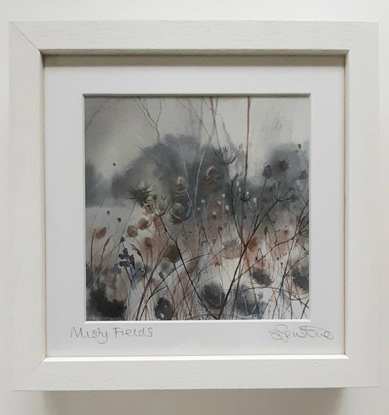 May include: A watercolor painting of a misty field with tall grasses and wildflowers. The painting is framed in a white frame and signed "Misty Fields" in the bottom left corner and "Ben Stowe" in the bottom right corner.