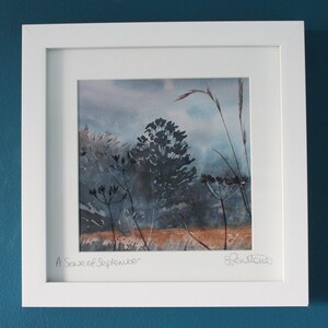 May include: A framed watercolor painting of a landscape with tall grasses and trees in shades of blue and brown. The title "A Sense of September" is written in the bottom left corner and the artist's signature is in the bottom right corner.