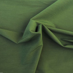 May include: A close-up of a smooth, dark green fabric with a subtle sheen. The fabric is folded and draped, showcasing its texture and drape.