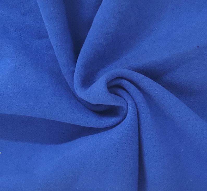 May include: A solid royal blue fabric with a soft, matte texture. The material is gathered in the center, creating deep, flowing folds and shadows that highlight the consistent, vibrant blue color across the entire surface of the textile.